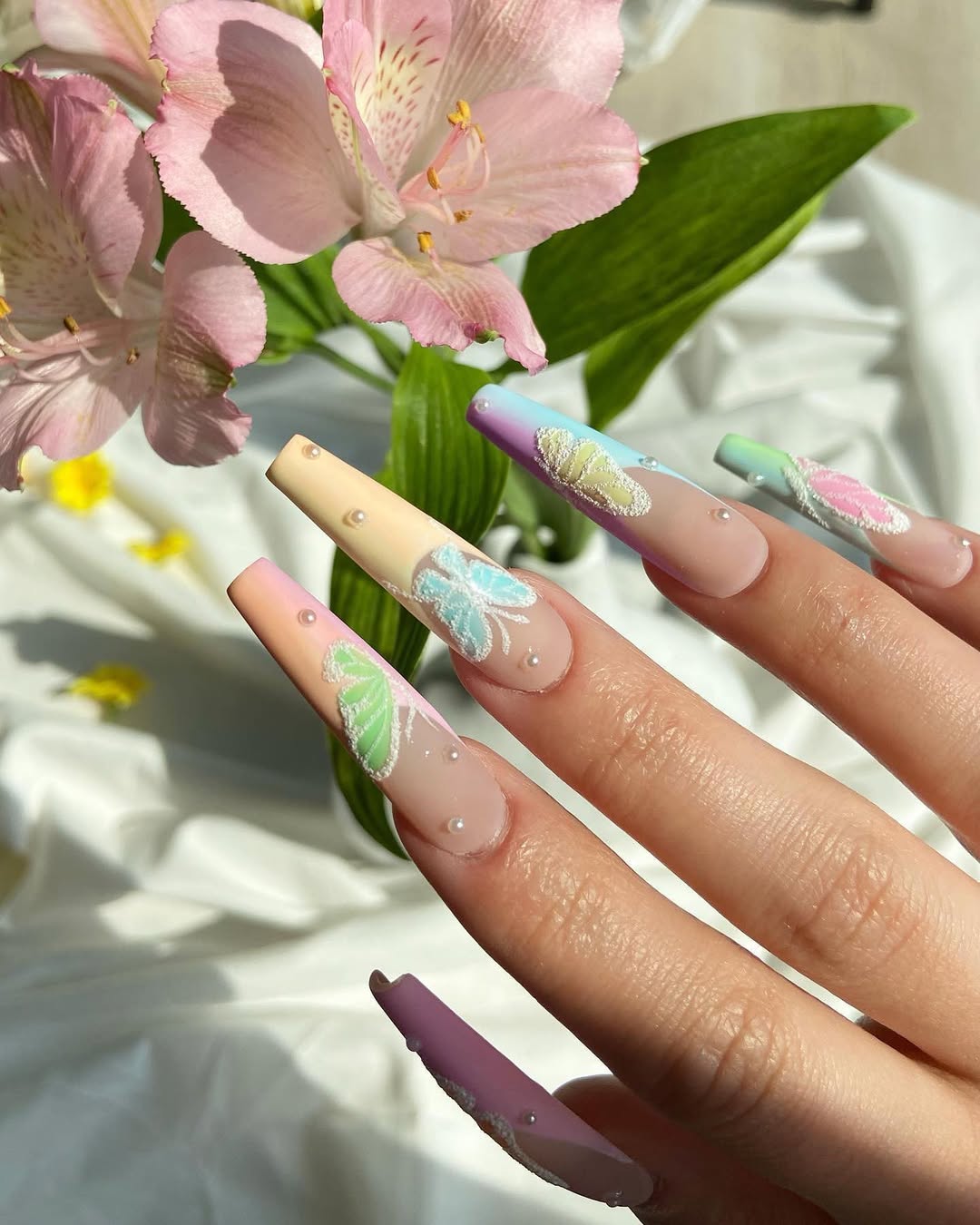 Close-up of a hand with decorative nails near pink flowers