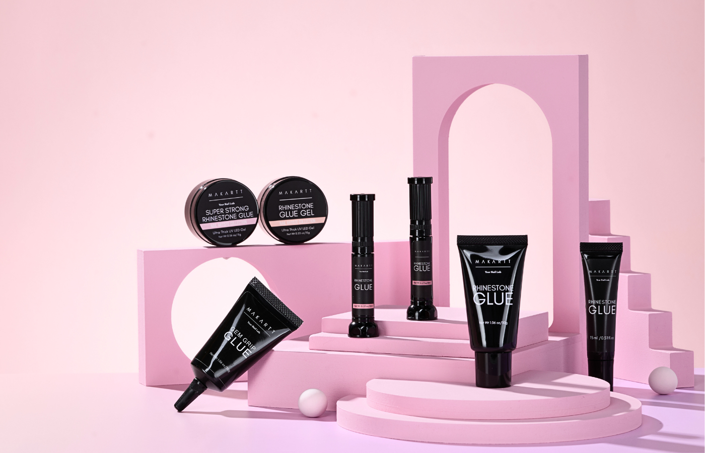 Makeup products including bottles and jars on a pink platform with a pink archway in the background.
